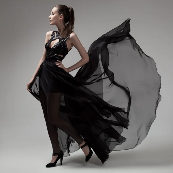 Mulher de moda em fluttering vestido preto. Fundo cinzento . — Fotografia de Stock