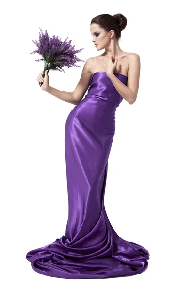 Schoonheid van de jonge vrouw in paarse jurk met bloem. — Stockfoto