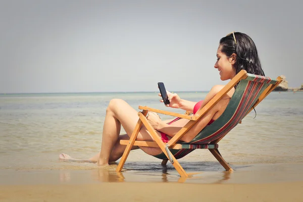 Mulher mensagens de texto na praia — Fotografia de Stock