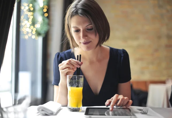 Donna che beve succo e utilizza compresse — Foto Stock