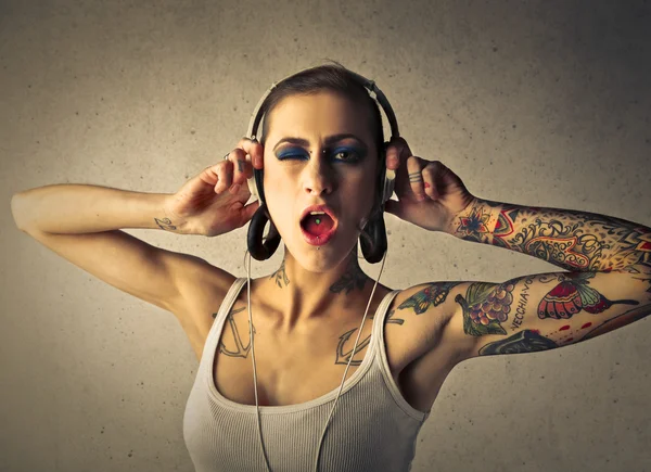 Татуированная женщина слушает музыку — стоковое фото