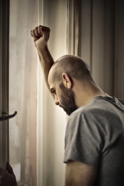 Rozrušený muž dívá z okna — Stock fotografie