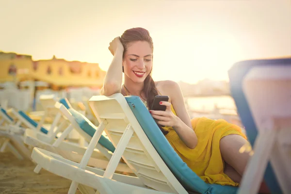 Vrouw texting op het strand — Stockfoto