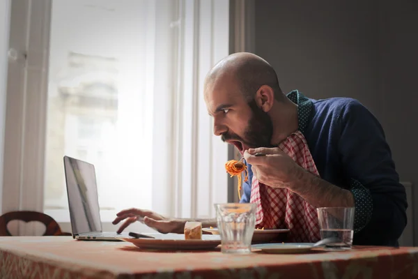 Man pasta eten en zijn telefoon controleren — Stockfoto