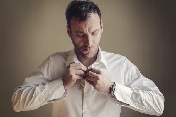 Een man knoopt zijn shirt dicht. — Stockfoto