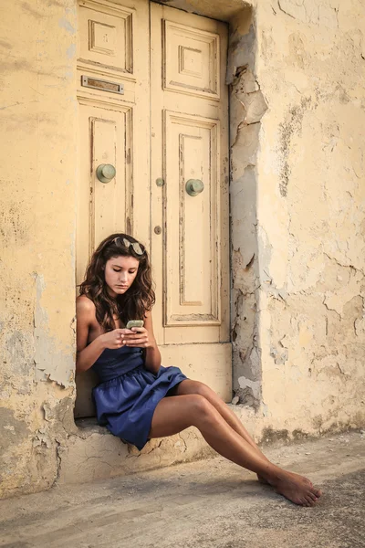 Young woman in blue dress texting on the phone — Stock Photo, Image