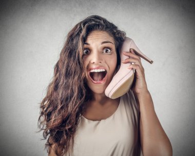 Excited girl talking on the phone, using a high-heeled shoe clipart