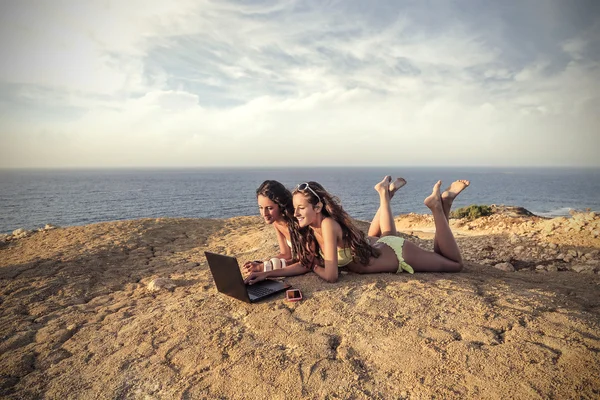 Two friends playing compuer games at the beach — Stock Photo, Image