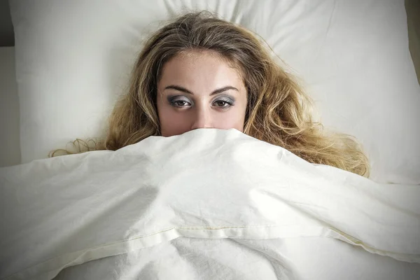 Ragazza assonnata nel suo letto sotto le lenzuola — Foto Stock