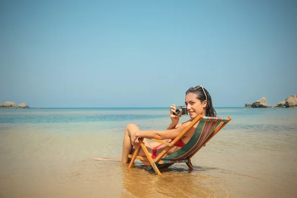 Ung kvinna sitter vid stranden tar en bild — Stockfoto