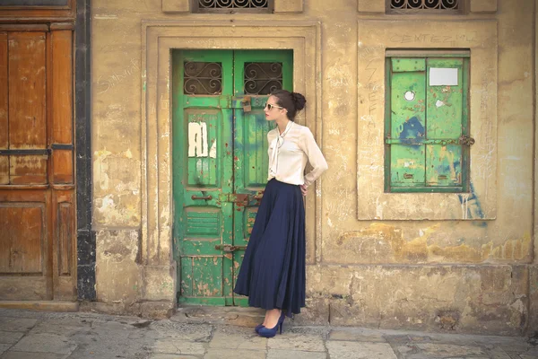 Красива жінка стоїть поруч із зеленими дверима — стокове фото