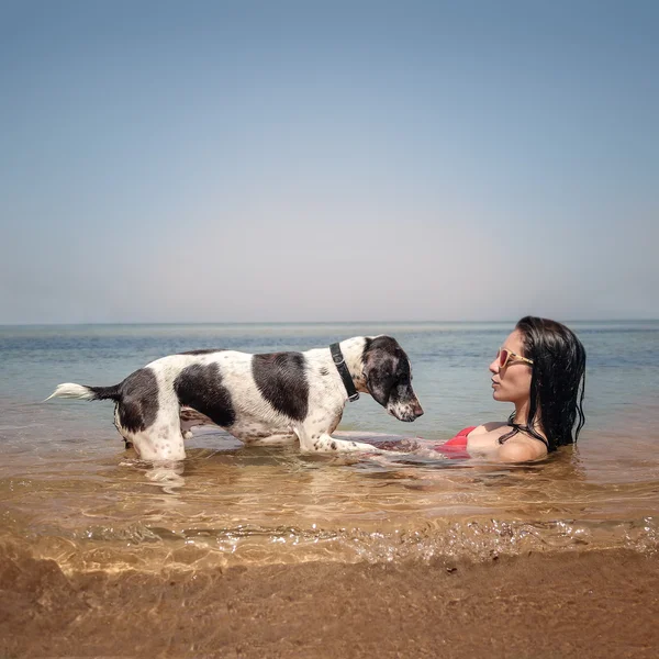 Junge Frau sitzt mit ihrem Hund im Wasser — Stockfoto