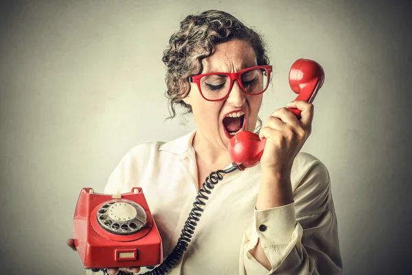 Jovem mulher gritando em um telefone antiquado vermelho — Fotografia de Stock