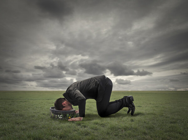 Бизнесмен смотрит в чашу на земле в мусорном поле
