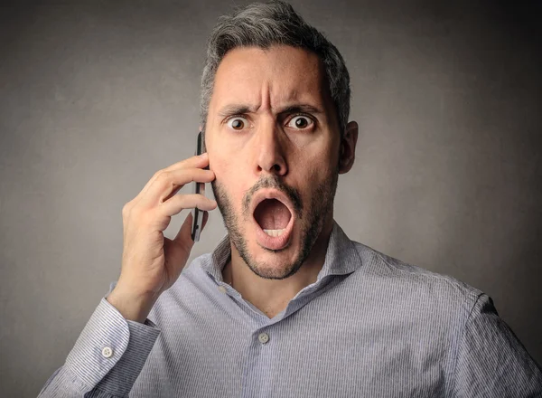 Шокированный человек делает телефонный звонок — стоковое фото