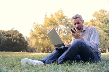 Kızgın adam akıllı telefonunu doğru parkta otururken bağırarak