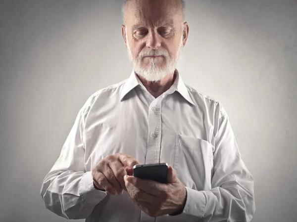 Homem idoso usando um telefone inteligente — Fotografia de Stock