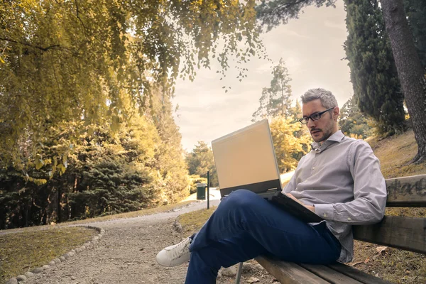 Homme assis sur un banc au parc — Photo