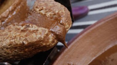 Geleneksel bir Fas değirmen taşı olan öğütücü taş ile kaplı Argan çekirdeklerine yakın çekim. Hamur, ünlü Argan yağını çıkarmak için kullanılacak. Yağ yağ asitleri açısından zengindir ve yemek ve kozmetik ürünlerinde kullanılır..