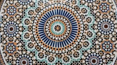 Colorful zellige pattern in traditional Islamic geometric design from a public fountain in Marrakech, Morocco. Made with natural colors from indigo, saffron, mint, kohl. Camera movement zooming in.