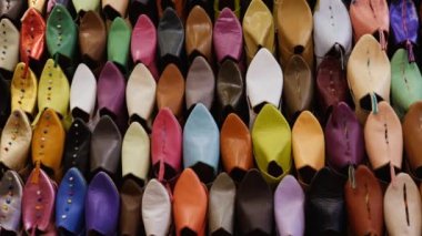 Authentic colorful Moroccan slippers (babouches), displayed on a wall, in the medina of Marrakech (Marrakesh), Morocco. Camera movement from right to left.