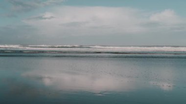 Sahilde ve bulutlarda yansıma, sakin doğa sahnesi gelen dalgalar, sabahın erken saatlerinde. Meditasyoncu, rahatlatıcı SPA konsepti, rahatlatıcı arka plan görüntüleri. Yavaş çekim.