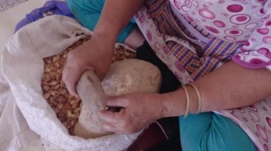 Faslı bir kadın geleneksel el yapımı Argan yağı üretimi için Argan cevizlerinin dış kabuğunu açıyor. Meşhur Argan yağı fındıkların içindeki çekirdeklerden elde edilir. Yağ yağ asitleri açısından zengindir ve yemek ve kozmetik ürünlerinde kullanılır..