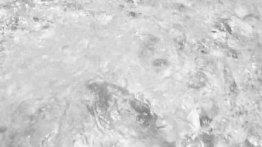 Parlak su, güneş yansımalı bir havuza dökülüyor. Siyah ve beyaz soyut arkaplan görüntüleri.