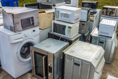 Ev İçi Başvuru Koleksiyonu (Fırınlar, Mikrodalgalar ve Çamaşır Makineleri) Bir Döküntü veya Geri Dönüşüm Merkezinde Solda