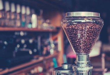 Fotokopi uzayı olan bir kahve dükkanındaki İtalyan espresso makinesine eklenmiş öğütücüde kavrulmuş kahve çekirdekleri.