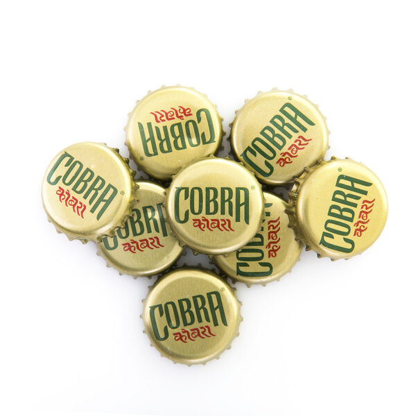 Pile Of Cobra Beer Bottle Tops on a White Background