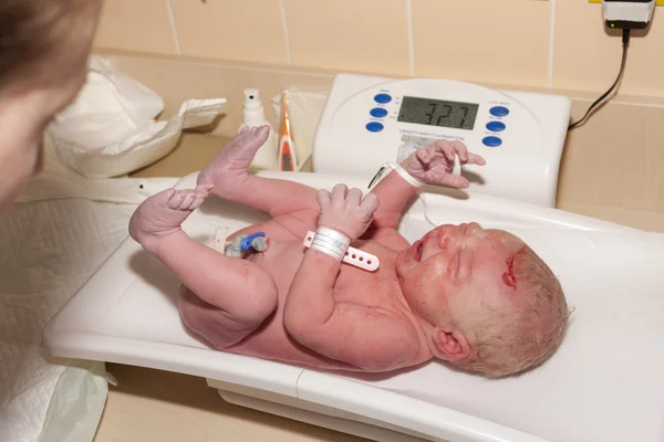Newborn on weight scale — Stock Photo, Image