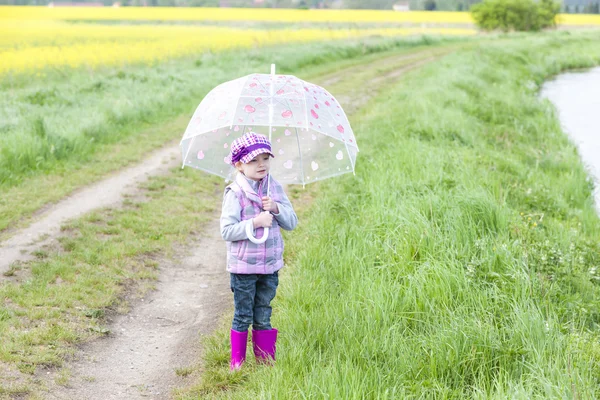 Liten flicka med paraply i vår natur — Stockfoto