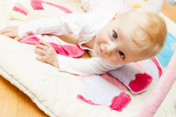 Baby flicka liggande på spelar matta — Stockfoto