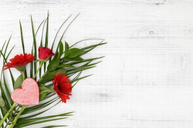 Beyaz ahşap arka planda kırmızı kalpli kırmızı çiçekler.