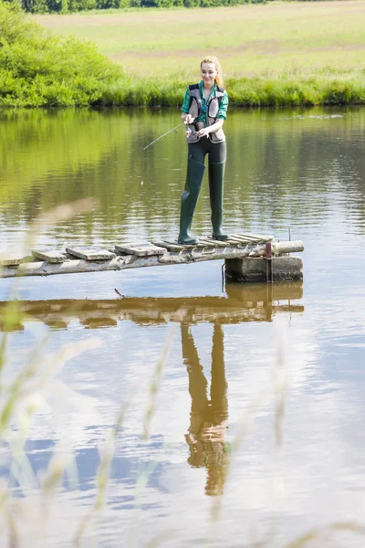 Young woman fishing on pier at pond — Stock Photo, Image