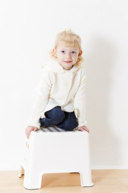 küçük kız beyaz kazak giyen diz çökmüş