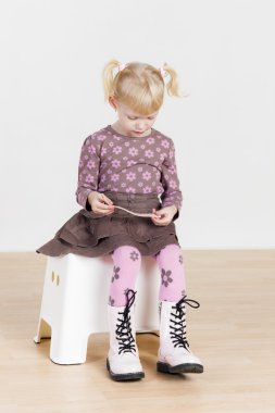 küçük kız bir bilezik ile oturuyor