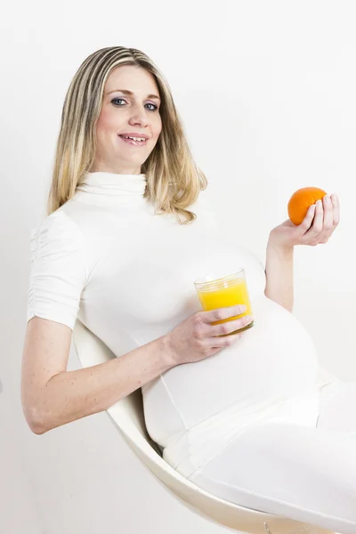 Portrait de femme enceinte avec un verre de jus d'orange et un o — Photo