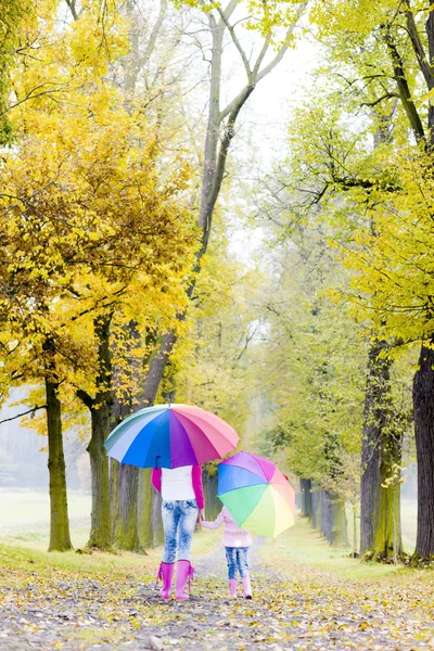 Mère et sa fille avec parasols dans la ruelle automnale — Photo