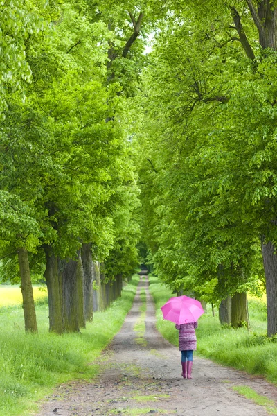 Vrouw dragen van rubber laarzen met paraplu in voorjaar steegje — Stockfoto