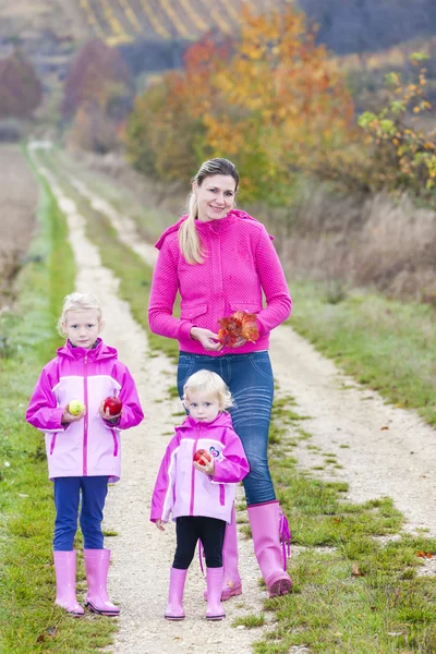 Mutter und ihre Töchter in herbstlicher Natur mit Äpfeln — Stockfoto