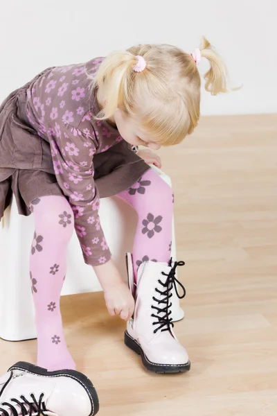 Little girl putting on boots — Stock Photo, Image