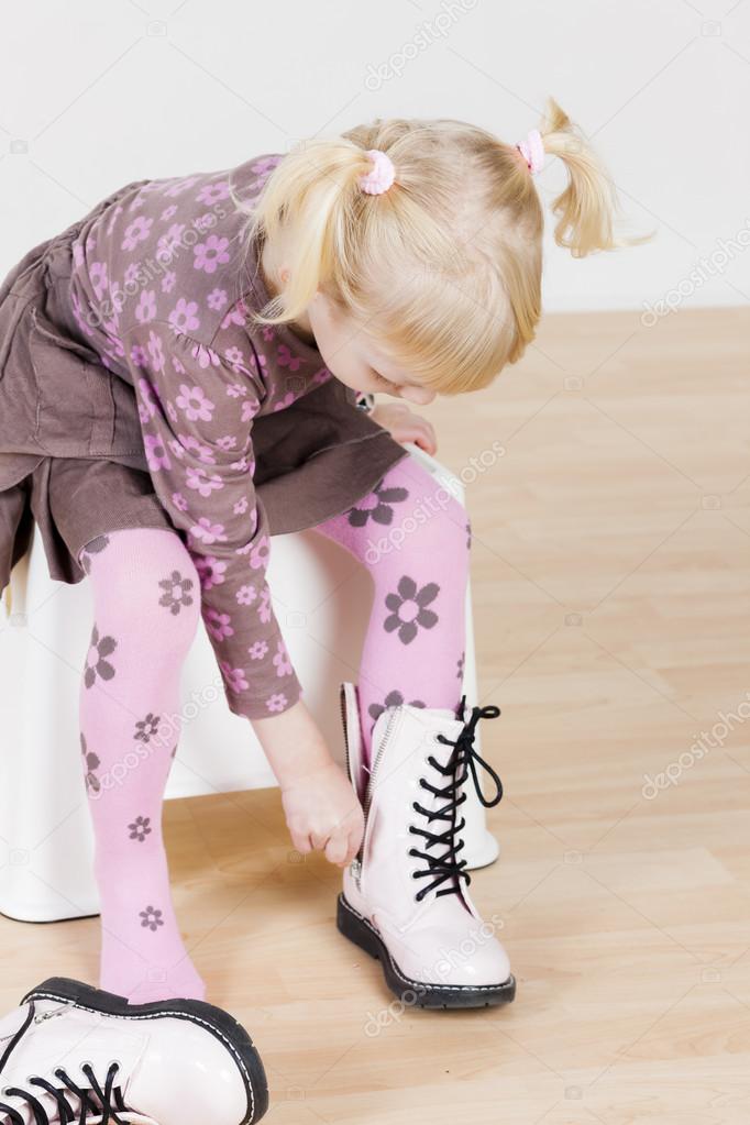 Little girl putting on boots — Stock Photo © #56299973