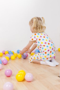Küçük kız toplarla oynuyor.