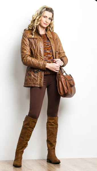 Standing woman wearing brown clothes and boots with a handbag — Stock Photo, Image