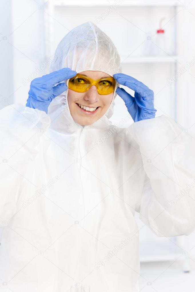 young woman with protective glasses and coat in laboratory