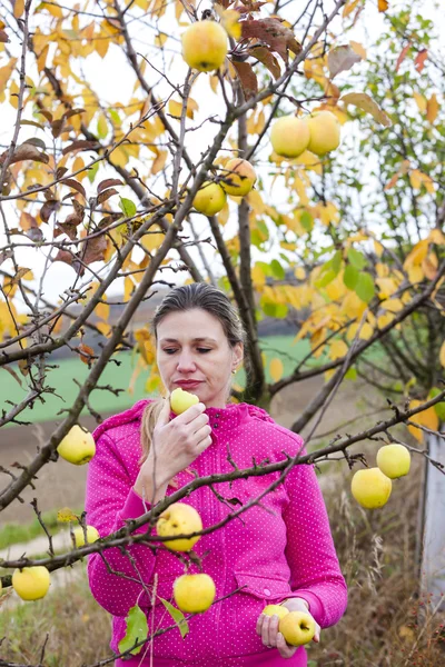 Woman with autumnal apple tree eating an apple — Stock Photo, Image