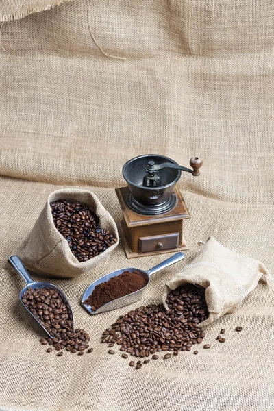 Still life of coffee beans in jute bags with coffee grinder — Stock Photo, Image