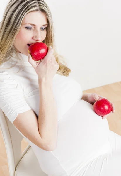 Femme enceinte mangeant de la pomme rouge — Photo